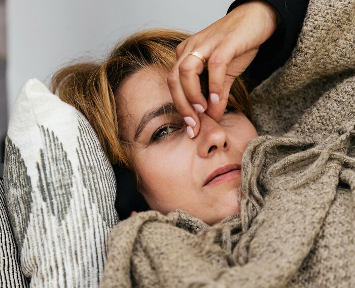 Person lying down looking upset and covering part of their face, sharing sounds of being extremely angry.