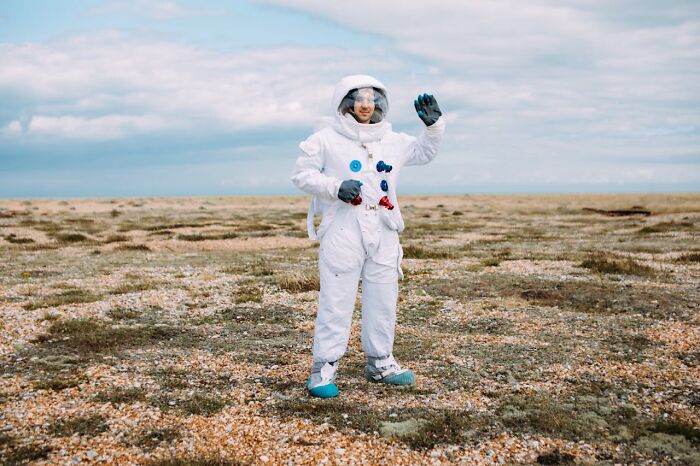 Person in an astronaut suit standing on barren land, representing unusual jobs for ultra-wealthy people.