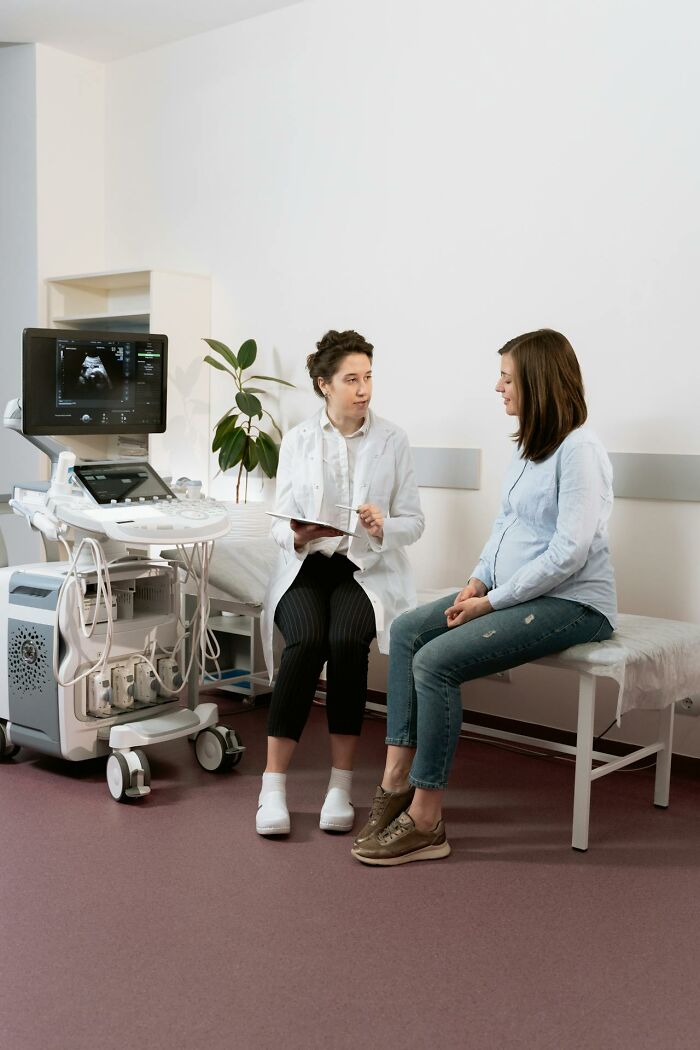 Doctor consulting a pregnant woman in a medical room with ultrasound equipment, highlighting things women are not allowed to do.