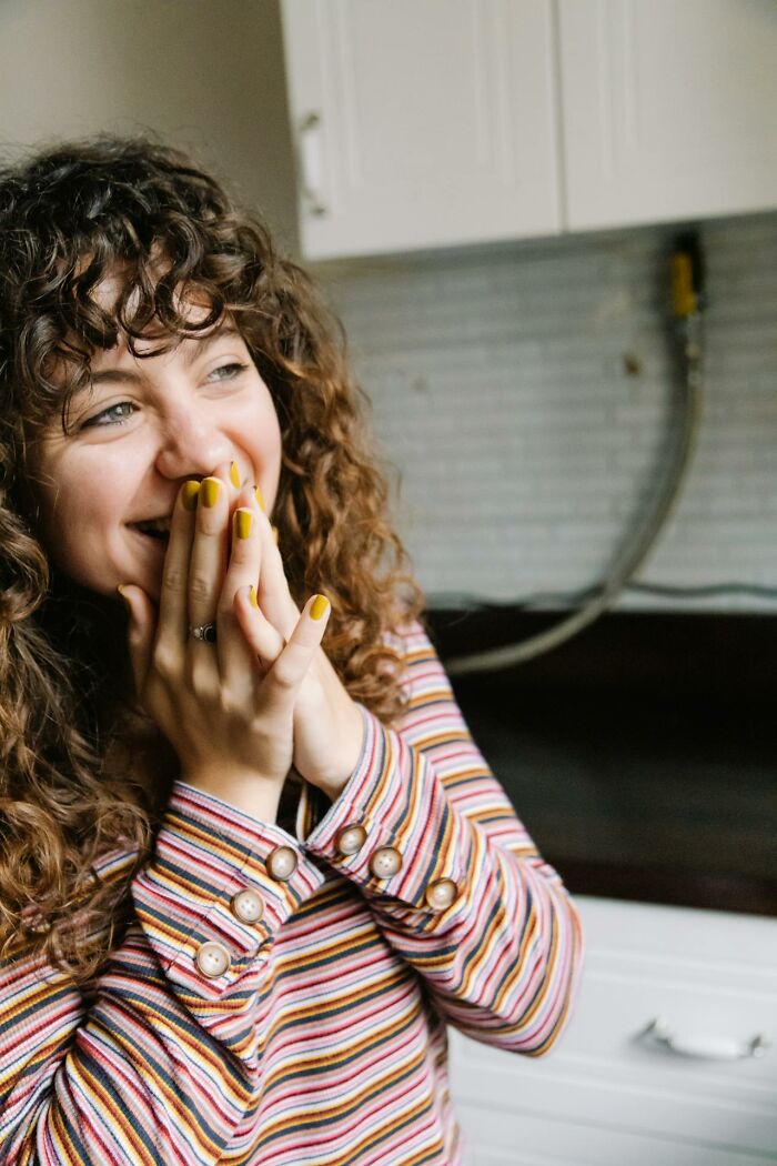 Woman with curly hair smiling in striped shirt, reacting with disbelief to unbelievable but true statements.