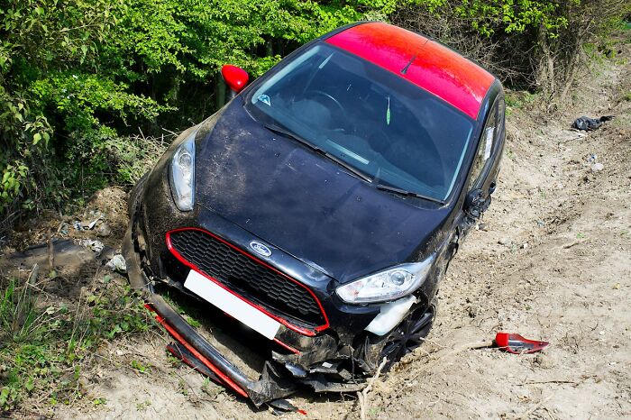 Damaged black and red car stuck off-road, symbolizing the impact of villains in someone else’s story.