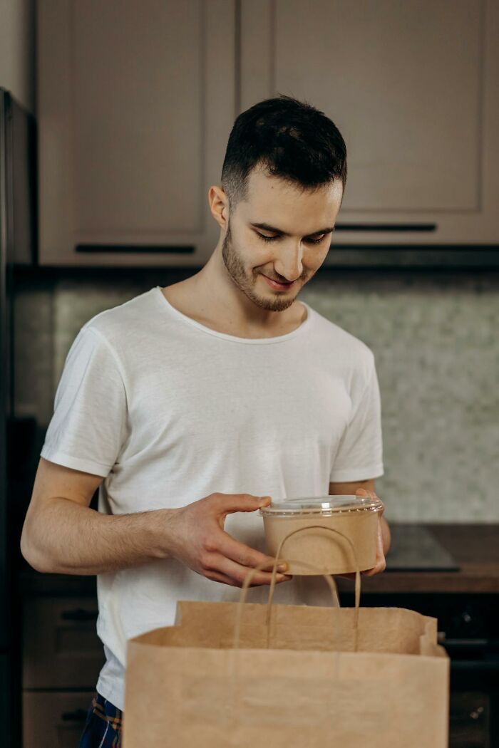 Man in a white shirt unpacking food containers from a paper bag, illustrating unbelievable things that were actually true.