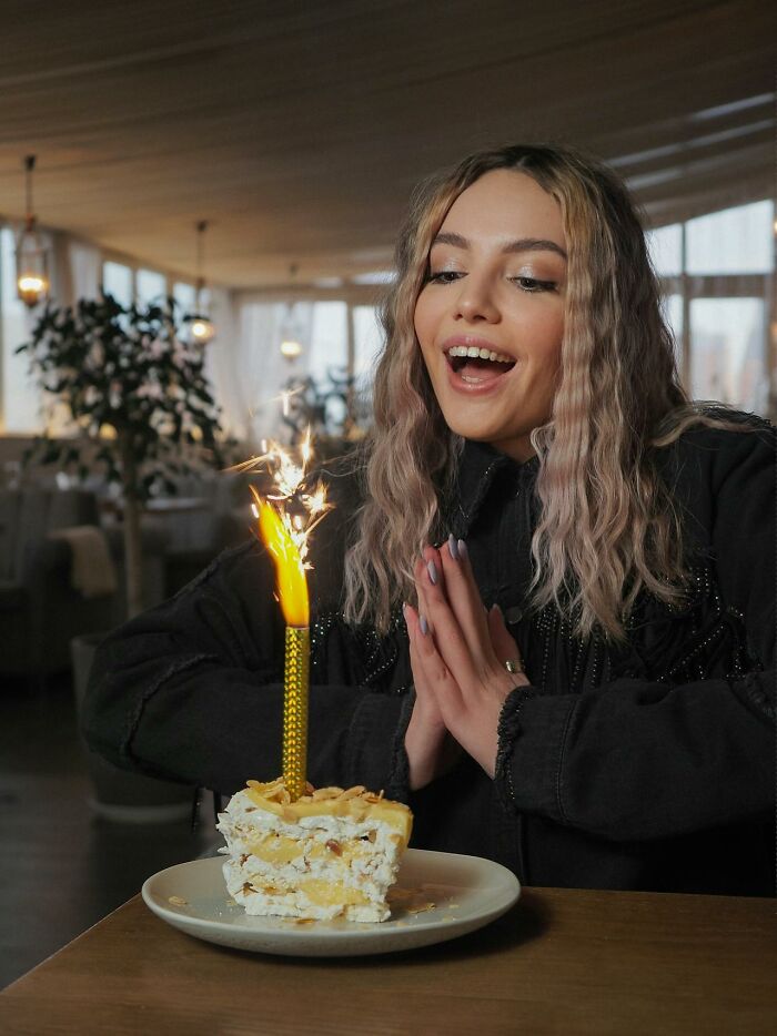 Young woman excitedly watching a sparkling candle on a cake, capturing unbelievable moments that are actually true.