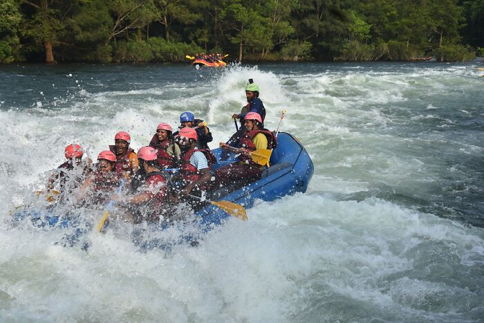 Group white water rafting on rapid river, capturing the moment that made them say definitely dead but survived.