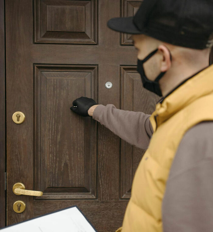 Person wearing a mask and gloves knocking on a door, evoking a creepy story atmosphere for dark woods campfire tales.