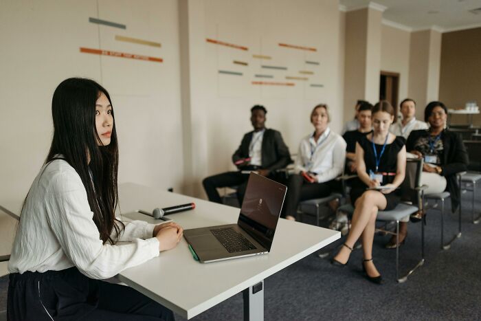 Young woman with laptop presenting at a meeting, illustrating subtle ways women have noticed misogyny in daily life.