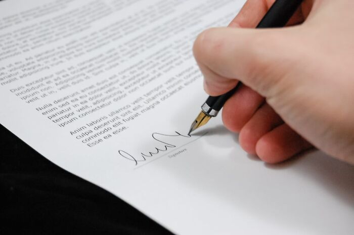 Close-up of a hand signing a document with a fountain pen, symbolizing a critical moment related to getting fired.