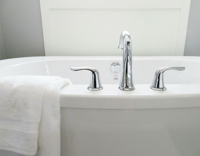 Modern bathtub faucet with clean white towel in a bright bathroom, illustrating patient hygiene and doctor visits.