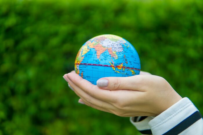 Hand holding a small globe representing geography IQ and open-ended questions for educational challenge. Hand holding a small globe representing geography IQ and open-ended questions for educational challenge.