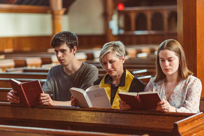 Three people sitting in church pews, reading books, capturing the contrast of sweet facade and hidden manipulation.