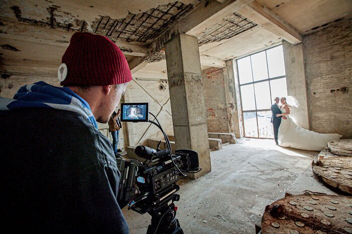 Videographer filming a bride and groom in an abandoned building, illustrating villain impact in someone else’s story.