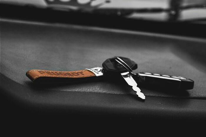 Keys and a leather key fob resting on a dark surface, symbolizing subtle ways misogyny creeps into daily lives.