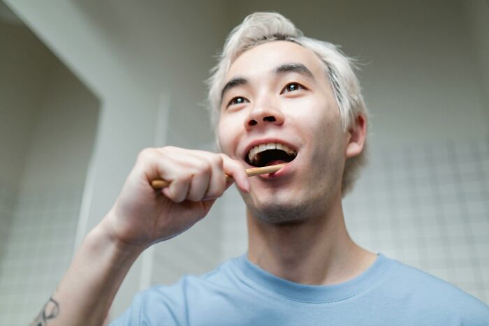 Young man with light hair brushing teeth, symbolizing moments people online revealed falling out of love.