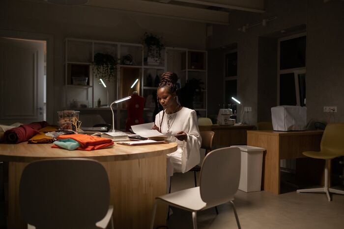 Woman reviewing documents in a dimly lit workspace, illustrating jobs for ultra-wealthy people in exclusive roles.