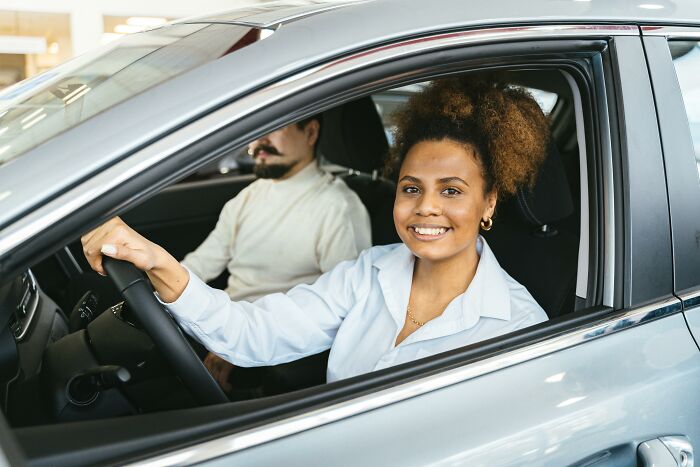 Woman smiling while sitting in a car with a man in the passenger seat, illustrating subtle ways misogyny appears daily.