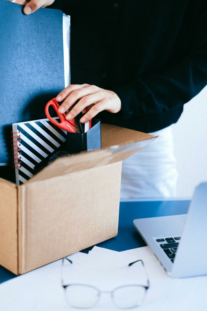 Person packing office supplies in a box, symbolizing the villain in someone else’s story who ruined their life.