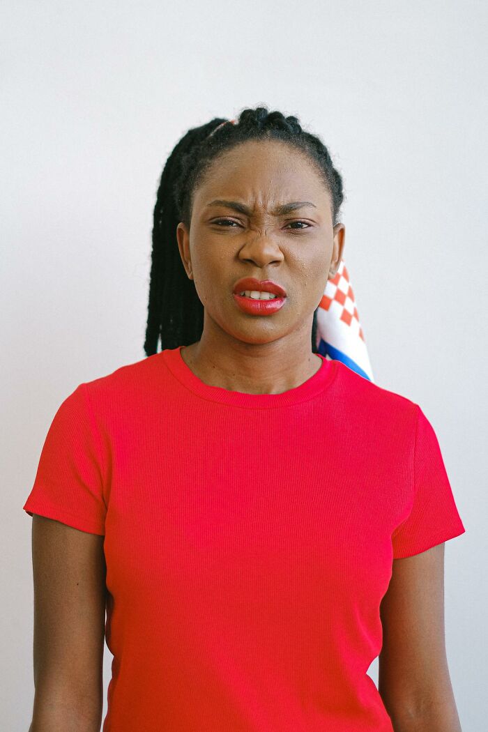 Woman wearing red shirt with a frustrated expression, representing things women are not allowed to do that men can do freely.