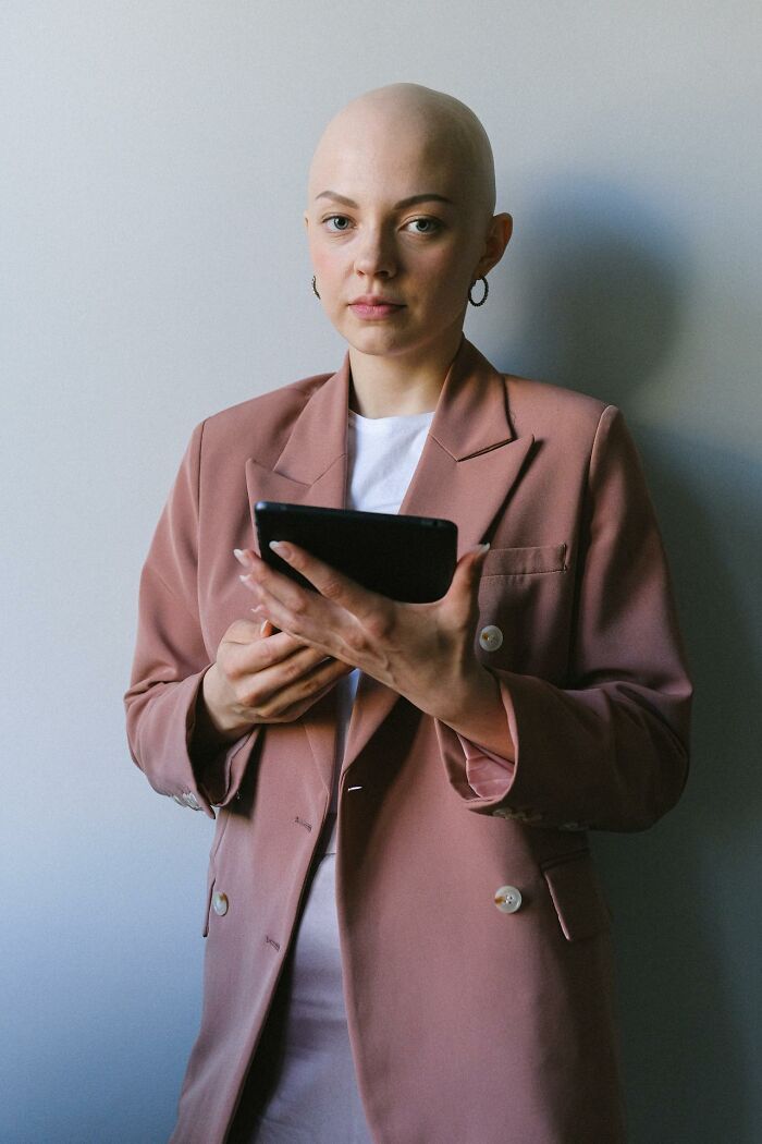 Woman holding tablet wearing a pink blazer, representing topics about things women are not allowed to do versus men freely.