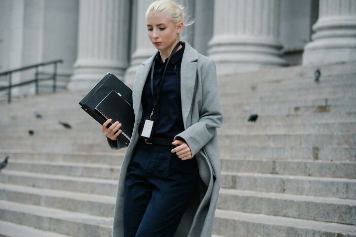 Young professional woman in a gray coat holding folders, representing common professions believed not relationship material.