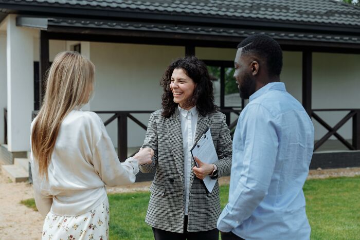 Three people meeting outdoors, with a woman shaking hands, illustrating subtle ways women notice misogyny in daily life.
