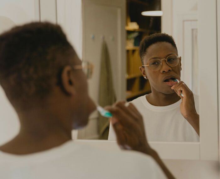 Person brushing teeth in bathroom mirror reflecting emotions related to nasty things exes did shocking partners