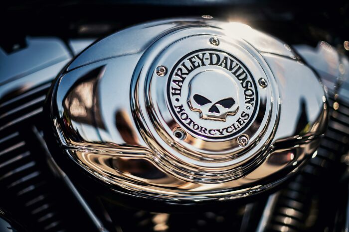 Close-up of a shiny Harley-Davidson motorcycle engine reflecting light as people share sounds extremely angry nearby.