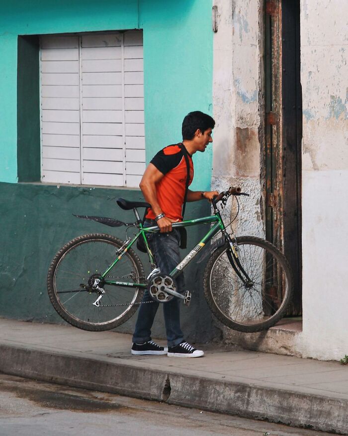 Man carrying a bicycle up a step on a street, illustrating unusual behavior linked to getting fired due to dumb mistakes.