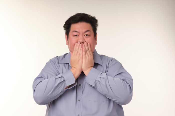 Man in a gray shirt with a shocked expression, covering mouth, representing unbelievable things that were actually true.