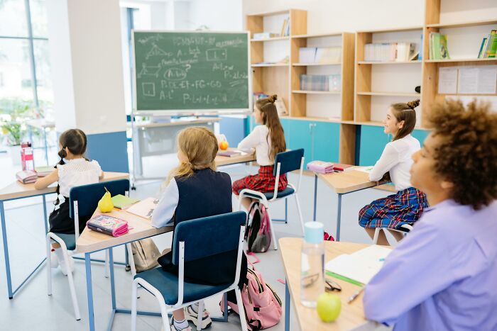 Classroom scene with students at desks and a chalkboard filled with school questions challenging even straight-A students.