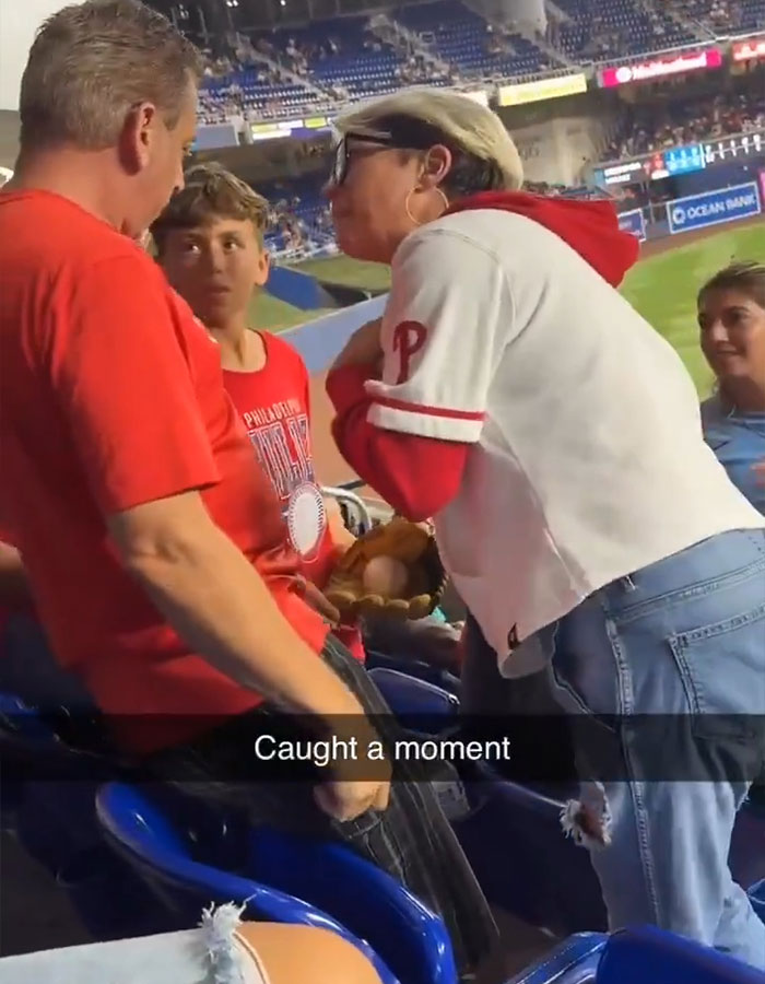 Woman in Phillies gear arguing with man and boy at stadium, sparking controversy over home run ball snatching incident.