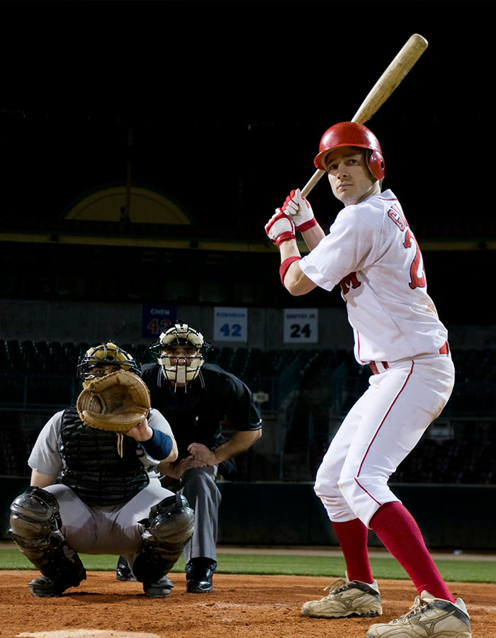 Baseball player at bat during night game with catcher and umpire ready, illustrating Phillies Karen incident context.