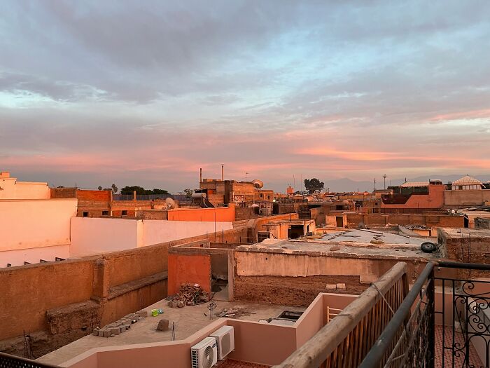 Sunset view over urban travel destinations showing rooftops and buildings under a colorful sky with soft clouds.