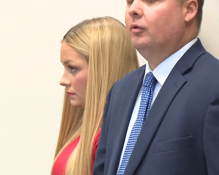 Woman with long blonde hair standing beside a man in a suit during a serious discussion about Kentucky cheerleader baby case. Woman with long blonde hair standing beside a man in a suit during a serious discussion about Kentucky cheerleader baby case.
