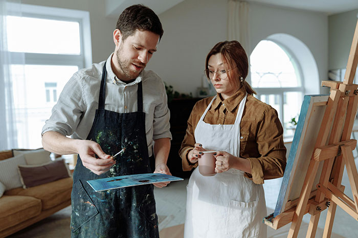 Couple exploring poly lifestyle and open marriage concepts while painting together in a bright art studio.