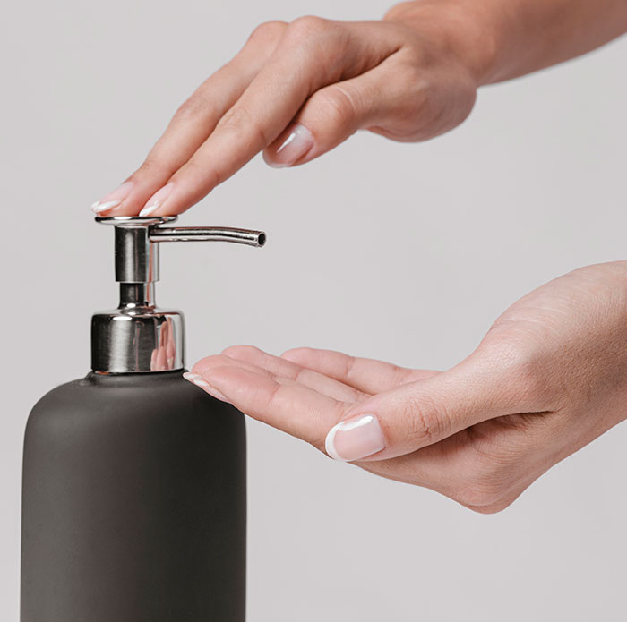 Hands pressing a pump dispenser on a black bottle, illustrating habits people who used to be poor can't get rid of.