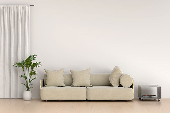 Minimalist living room with beige sofa and green plant, illustrating habits people who used to be poor can't get rid of.