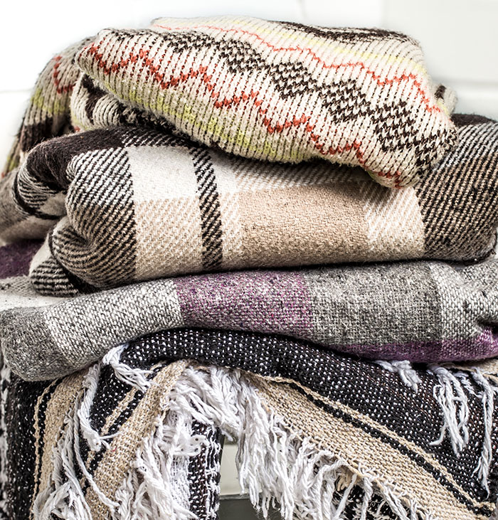Stack of warm sweaters and blankets representing habits people who used to be poor can't get rid of.