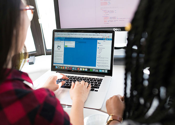 Two people collaborating on a laptop, demonstrating person product interaction in a modern work setting.