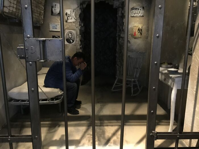 Man sitting inside a jail cell, illustrating Americans finding a loophole and using it in a confined space scenario.