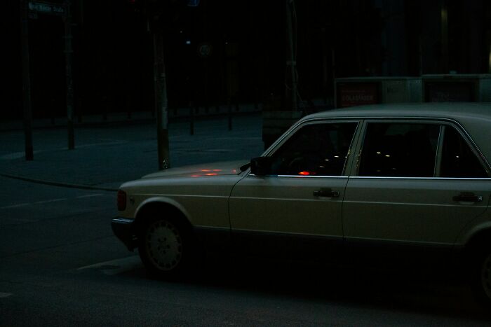 Vintage car parked on a dark street at night, evoking an eerie atmosphere for creepy stories in the dark woods.