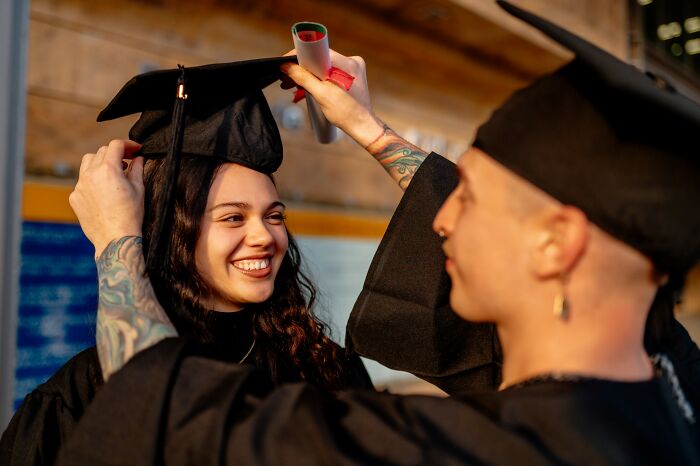 Two graduates in caps and gowns celebrating with a diploma, illustrating dumbest and out of touch moments shared.