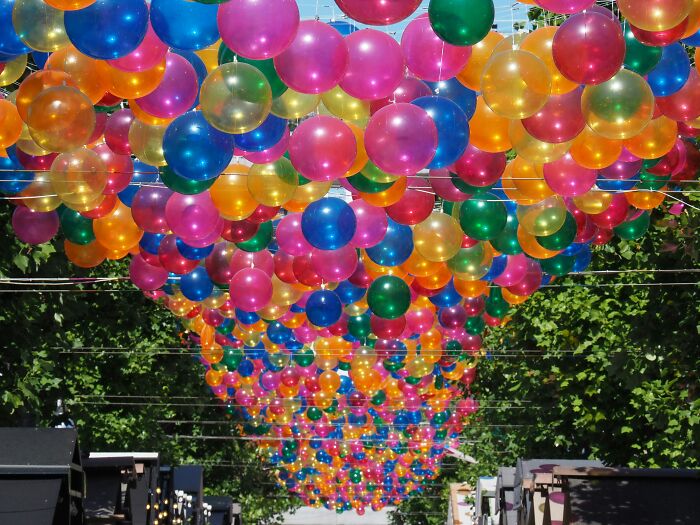 Colorful balloons hanging overhead along a street, illustrating overhyped products in a festive outdoor setting.