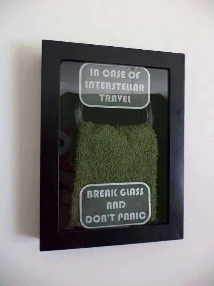 Framed emergency towel with text about interstellar travel and break glass instructions in humorous history meme style.