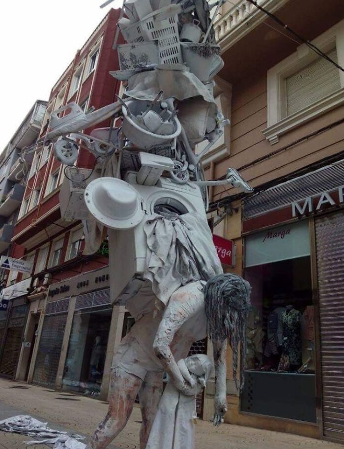 Street sculpture of a figure carrying household items, representing inspiring facts better than watching the news.