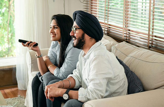 Two people sitting on a couch watching TV, symbolizing doctors breaking down accurate and inaccurate diagnoses from House M.D.