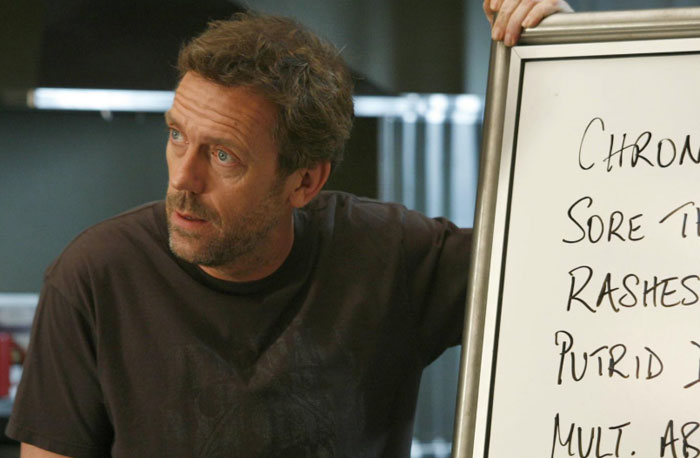 Actor Hugh Laurie as Dr. House speaking next to a whiteboard showing symptoms, illustrating accurate diagnoses from House M.D.