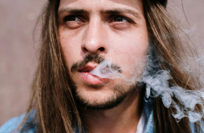Young man with long hair exhaling smoke, illustrating discussion on accurate and inaccurate diagnoses from House M.D.