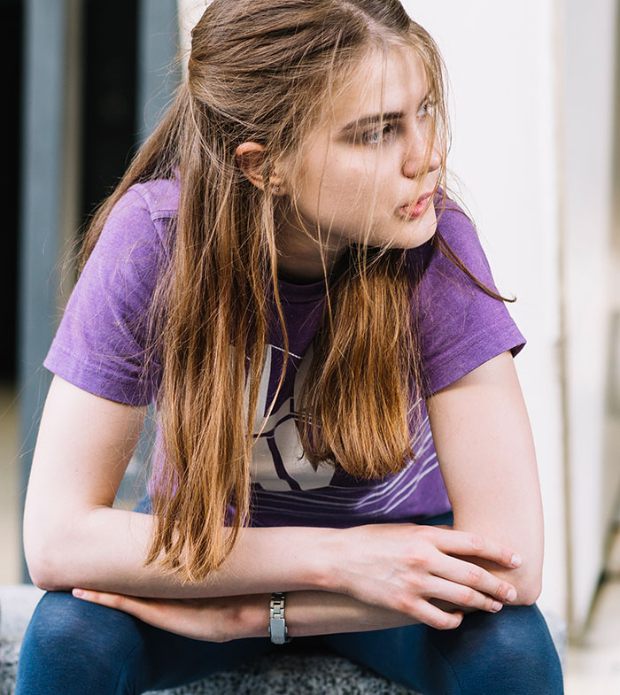 Young woman in a purple shirt sitting thoughtfully, reflecting the eerie mood of scary real-life stories people shudder to tell.