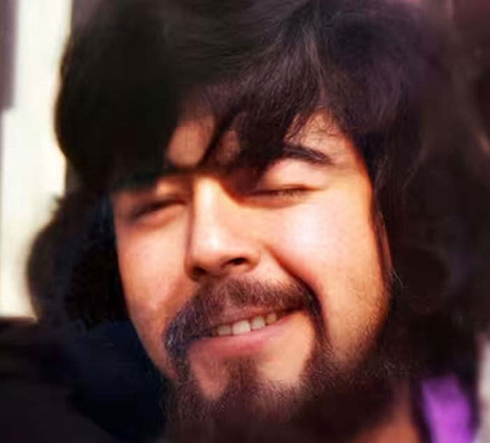 Close-up of a man with dark hair and beard, smiling slightly while sharing scary real-life stories that cause shuddering.