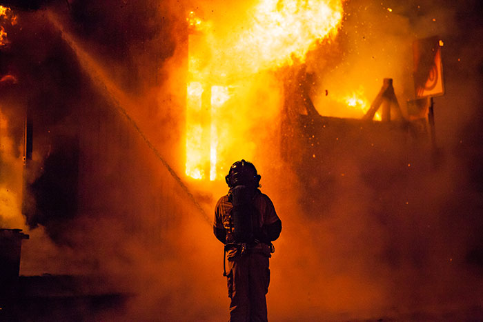 Firefighter battling intense flames at night, illustrating one of the scary real-life stories people shudder to tell.